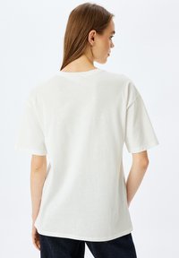 Hvid bomulds t-shirt med afslappet pasform, korte ærmer og rund hals. Minimalistisk design med en glat tekstur og ensfarvet ryg.