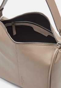 Beige Lederhandtasche mit glatter Textur, Reißverschluss und einem Innenfach. Das Innere ist mit schwarzem Stoff ausgekleidet. Minimalistisches Design.