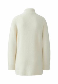 Pull crème avec un col montant en côtes, texture douce, coupe oversize et manches longues. Le dos présente un design simple et sans coutures.