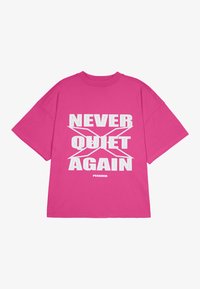 Roza oversize majica iz bombaža, ki vsebuje drzne bele napise "NEVER QUIET X AGAIN" in blagovno znamko na dnu.