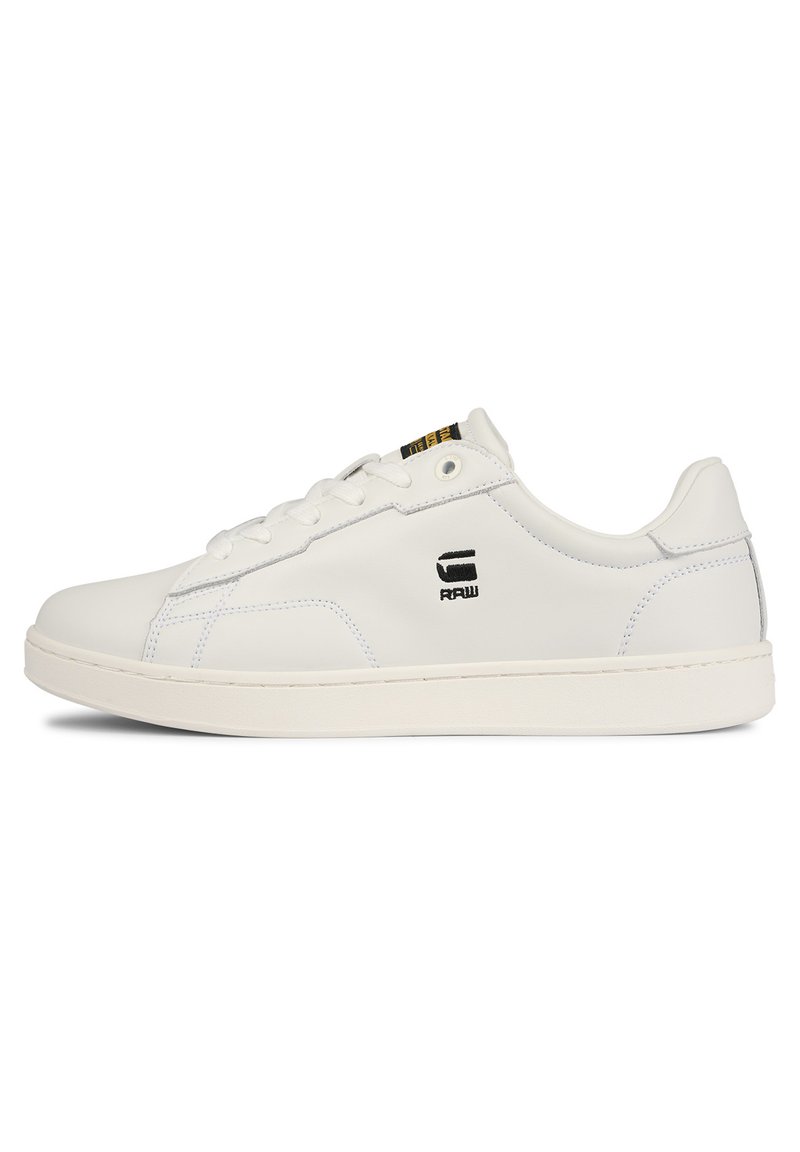 Baskets blanches en cuir avec un design à profil bas, présentant une finition texturée, un devant à lacets et un accent logo noir sur le côté.