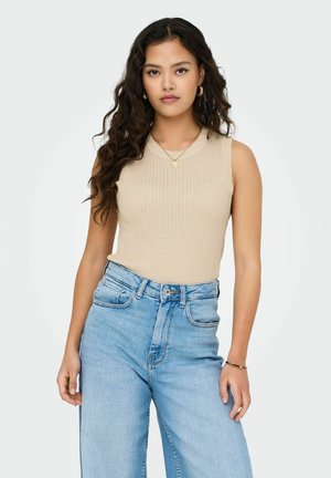 Débardeur sans manches beige à côtes associé à un jean taille haute bleu clair. La tenue présente un design minimaliste avec des détails de texture subtils.