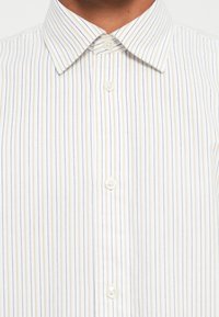 Camicia button-up a righe con sottili linee blu e arancioni su uno sfondo bianco. Con colletto, texture morbida e cinque bottoni.