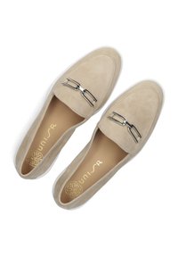 Beige suède loafers met een decoratieve zilveren gesp. Heeft een ronde neus en een witte rubberen zool. Het interieur heeft een gouden logo.