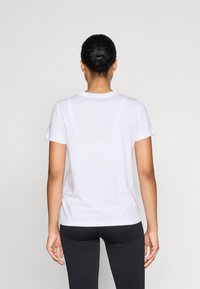 Balta īsām piedurknēm T-kreklā ar apaļu kakla izgriezumu, izgatavota no mīksta auduma. Aizmugure ir vienkārša, ar parastu piegriezumu, apvienota ar melniem legingiem.