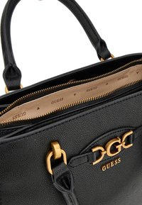 Borsa a tracolla in pelle nera granulosa con accessori dorati, manici superiori e chiusura lampo. L'interno presenta una fodera in tessuto marchiato.