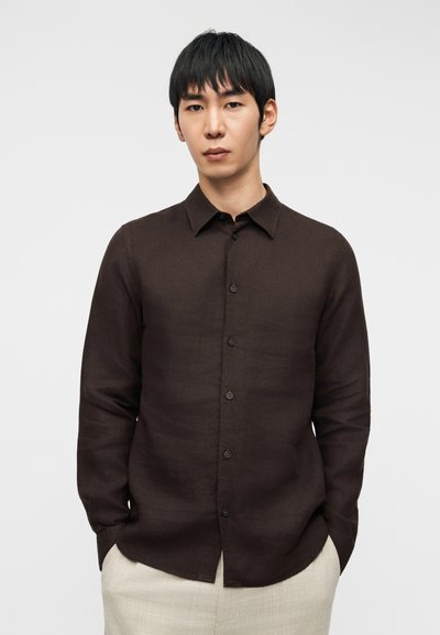 Σκούρο καφέ, πουκάμισο με μακριά μανίκια και κουμπιά, από λινό μείγμα, με κλασικό γιακά, κουμπιά στο μπροστινό μέρος και άνετη εφαρμογή, συνδυασμένο με ανοιχτόχρωμο παντελόνι.