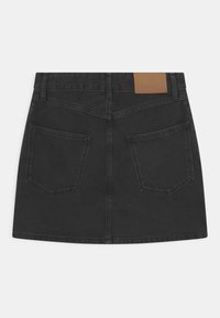 Musta farkkuseli, jossa on keskimäinen vyötärö, kaksi takataskua ja vaalea nahkalaatta takavyötäröllä.