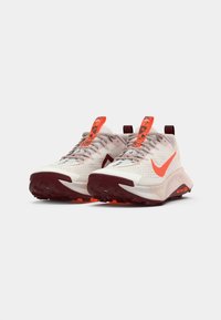 Lightweight athletic shoes with a cream upper, orange accents, breathable mesh, and rugged sole for traction. Reflective details on laces.