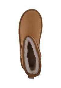 Vista desde arriba de una sola bota de invierno de ante marrón con forro de felpa blanca y tira de agarre sobre un fondo blanco.