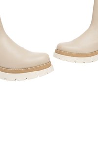 Stivali ankle beige con finitura in pelle liscia, punta rotonda e suola piattaforma spessa bianca con dettagli in legno.