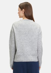 Grauer Strickpullover mit geripptem Saum und Ärmeln, der eine leichte Textur und eine lockere Passform aufweist. Die Rückansicht zeigt ein minimalistisches Design.