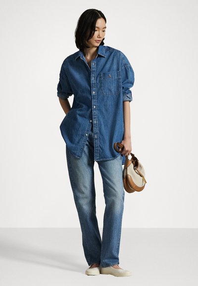 Jeansskjorta i mörkblått med knappstängning, oversize passform, bröstficka, uppvikta ärmar, tillsammans med ljusblå raka jeans och en liten väska.