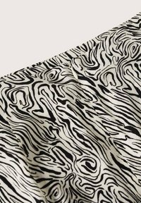 Tessuto a motivi in bianco e nero con linee ondulate e sinuose, che mette in mostra una texture liscia e una caduta morbida. Adatto per abbigliamento o decorazioni.