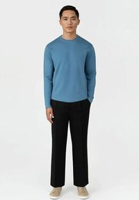 Lyseblå langermet hettegenser med rund hals, kombinert med svarte bukser og beige joggesko. Glatt tekstur, avslappet passform, minimalistisk design.