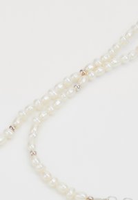 Collana di perle naturali con perle bianche irregolari e lucenti e accenti in argento, dotata di un gancio per la chiusura.
