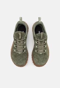 Zapatos de exterior de ante verde con textura perforada, que cuentan con cordones texturizados, una suela de goma y una lengüeta en el talón.