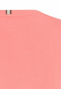 Koralfarvet bomulds t-shirt med rund halsudskæring, der har syninger langs kraven og en subtil tekstur.