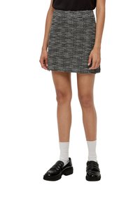Zwart-wit gestreepte minirok van gestructureerde stof, hoge taille en rechte snit, gecombineerd met zwarte loafers en witte kousen.