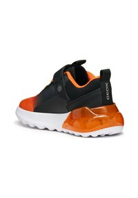 Sneaker nero e arancione con tacco testurizzato e lucido, fascia regolabile e suola in gomma bianca con forma arrotondata.