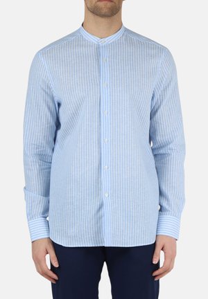 Uomo che indossa una camicia a righe verticali azzurro chiaro e bianca con collo alla coreana e pantaloni blu scuro.
