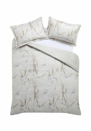 Doppelbett mit weißem und beigem Bettbezug mit Blumenmuster und zwei passenden Kissen auf einem weißen Spannbettlaken.