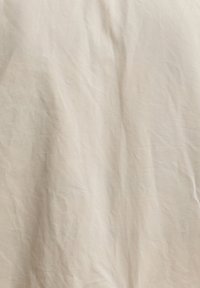 Υφή μπεζ ζαρωμένου υφάσματος με ορατές πτυχές και απαλές σκιές.