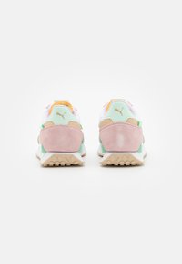Zapatillas Puma con una combinación de colores en tonos pastel, que incluyen malla blanca, ante rosa y acentos verdes. El diseño trasero muestra un logotipo prominente en el talón.