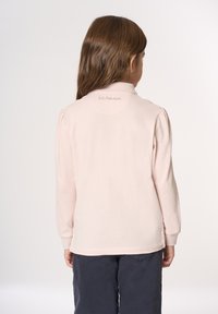 Polo a maniche lunghe rosa pallido con colletto a pieghe e logo U.S. Polo Assn. ricamato sul retro. Tessuto morbido e strutturato.