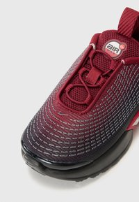 Maroon and black sneaker with mesh upper, reflective stitching, padded collar, and air cushioning in the sole. Rounded toe and lace closure.