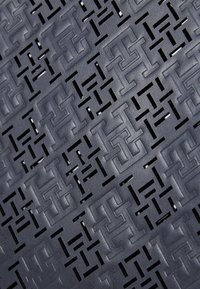 Sötétkék bőrfelület geometrikus kivágásos mintával, amely egymásba kapcsolódó formákat alkot; texturált felület, dombornyomott részletekkel.