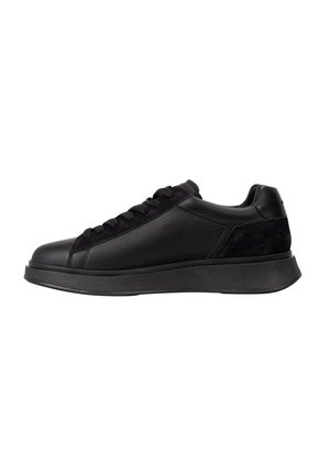 Sneaker negro de caña baja con cuero texturizado, acentos de ante, punta redonda, cordones en la parte frontal y suela de goma gruesa, visto de lado.