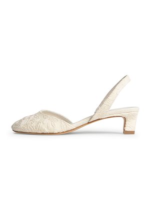 Zapato slingback color crema con tacón bajo de bloque, puntera puntiaguda y bordado floral texturizado en la parte superior de tela.