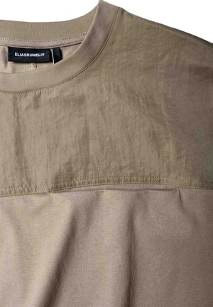 T-shirt beige à manches courtes avec un design à panneaux ton sur ton en tissu texturé. Comprend un col ras-du-cou côtelé et des détails de couture apparents.