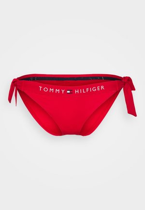 Parte inferior de bikini vermelho com laço lateral, apresentando uma faixa com o logótipo "TOMMY HILFIGER" em branco na cintura, feita de tecido suave.