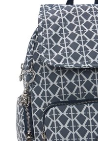 Laukkusininen selkäreppu, jossa on geometrinen harmaa kuvio, metallivetoketju ja irrotettava charmikoru. Valmistettu kestävästä kankaasta ja sillä on jämäkkä muoto.