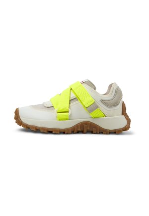 Sportschuh mit einem weißen und beigen Oberteil, ausgestattet mit einem leuchtend gelben Riemen über der Mittelpartie und einer strukturierten Gummisohle für besseren Halt.