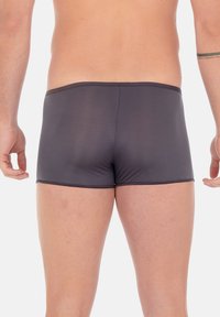 Boxer da uomo aderenti in grigio scuro, realizzati in materiale elastico con una texture liscia e un design minimale. La cintura si posiziona sui fianchi.