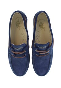Zapatos náuticos de ante azul marino con cordones de cuero marrón, plantilla perforada y marca U.S. Polo Assn. en la plantilla.