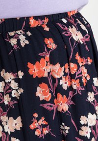 Saia floral em tecido azul marinho, com padrões florais abstratos em laranja, rosa e creme, e um cós elástico para conforto.