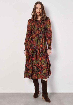 Long, patterned dress with smocked bodice, features floral designs in green, red, and orange. Pair with brown knee-high boots.