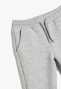 Grijze gewatteerde sweatpants met een verstelbare tailleband, voorzien van zijzakken en een diamantpatroon in de stof.