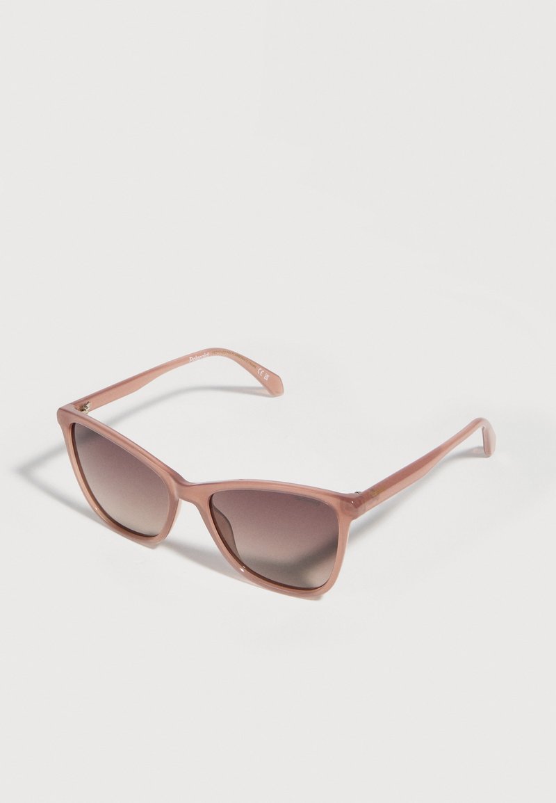 Lunettes de soleil carrées à monture translucide marron avec des verres dégradés foncés, posées sur une surface claire.