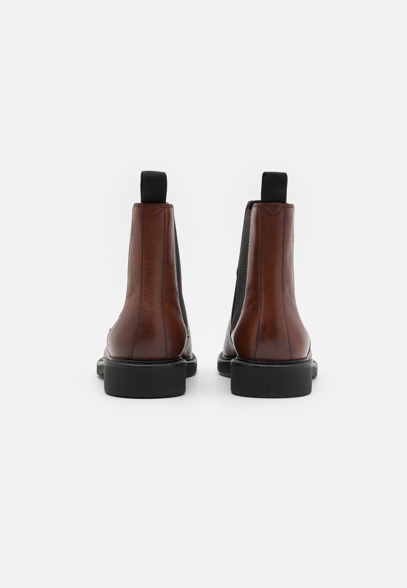 Bruna läder Chelsea-boots med svarta elastiska sidor, en strömlinjeformad design, rundade tår och hållbara svarta gummisulor.