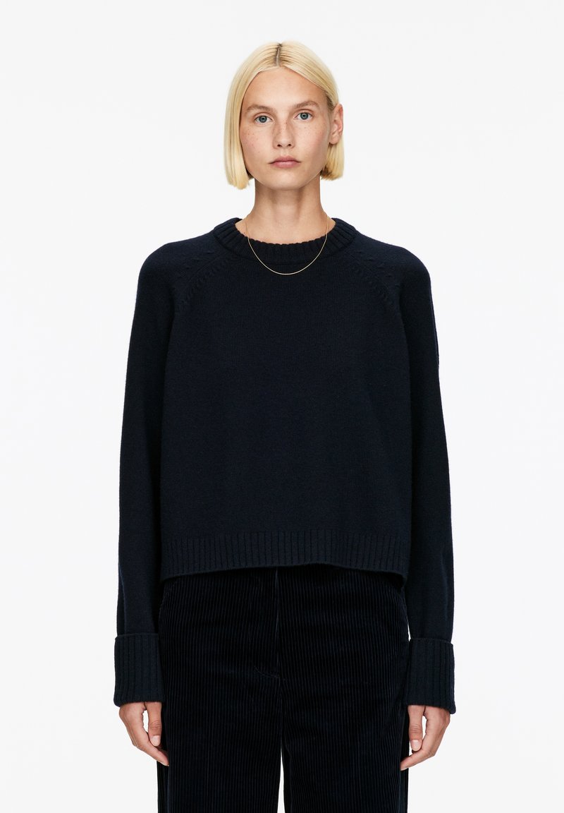 Marineblauer, gestrickter Pullover mit verkürztem Design, geripptem Saum und weiten Bündchen. Mit Rundhalsausschnitt und strukturierten Details auf den Schultern.