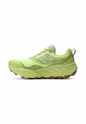 Lichtgroene New Balance hardloopschoen met dikke zool, textuurstof bovenwerk en reflecterend "N"-logo aan de zijkant, in profiel weergegeven tegen een witte achtergrond.