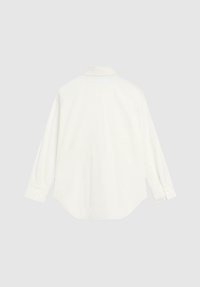 Bílá košile s dlouhým rukávem se standardním límečkem, manžetami na knoflíky a zakřiveným lemem, vyrobená z měkké látky s hladkou texturou.