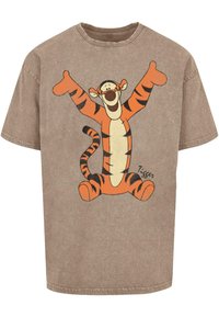 Rudas medvilninis marškinėliai su dideliu Tigger piešiniu, turinčiu oranžinių ir juodų dryžių, besišypsančiu, pakeltomis rankomis ir ženklu apačioje.