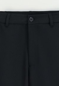 Pantalons noirs ajustés en tissu lisse, à devant plat, avec passants de ceinture et fermeture à un bouton noir unique à la taille.