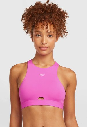 Ružová športová podprsenka s vysokým golierom, výrezmi vpredu a logom na hrudi. Vyrobená z elastickej, hladkej látky.